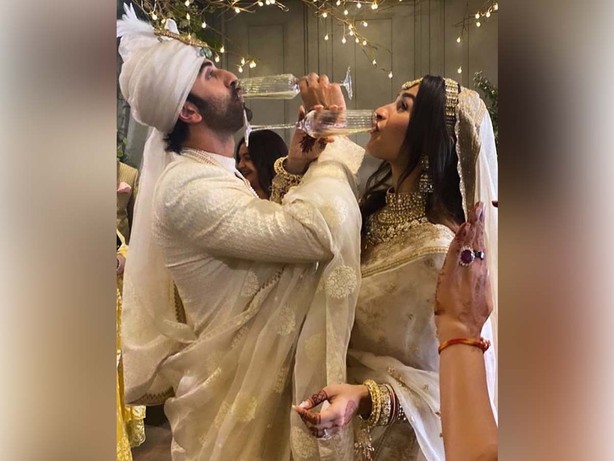 Newly wed Alia Bhatt and Ranbir Kapoor drink champagne with their arms crossing each other
